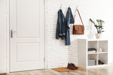 Stylish hallway interior with door, comfortable furniture and clothes on brick wallの写真素材