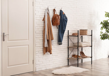 Stylish hallway interior with door, comfortable furniture and clothes on brick wallの写真素材