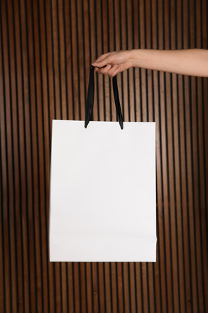 Woman holding paper shopping bag on wooden background. Mock up designの写真素材
