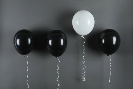 White balloon rising higher than others on black background. be differentの写真素材