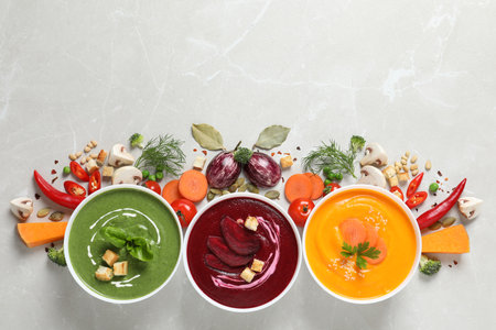 Various cream soups, ingredients and space for text on gray background, flat lay. Health foodの写真素材
