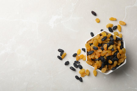 Bowl of raisins on gray background, top view with space for text. Dried fruit as a healthy snack