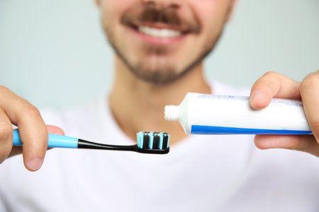 Man with toothbrush and paste on blurred background, closeupの写真素材