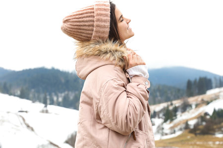 Young woman in warm clothes near snowy hill. winter holidays