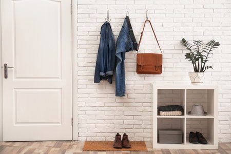 Stylish hallway interior with door, comfortable furniture and clothes on brick wallの写真素材