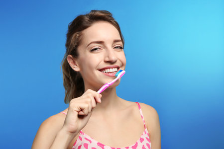 Portrait of young woman with toothbrush on color background. Space for textの写真素材