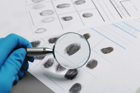 Criminalist exploring fingerprints with magnifying glass, closeupの写真素材
