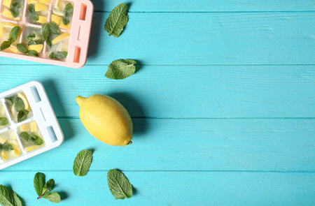 Flat lay composition with ice cube tray, mint and lemon on wooden background. Space for textの写真素材