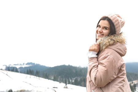 Young woman in warm clothes near snowy hill, space for text. winter holidays