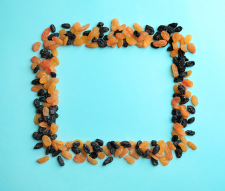 Frame made of raisins on color background, top view with space for text. Dried fruit as a healthy snackの写真素材