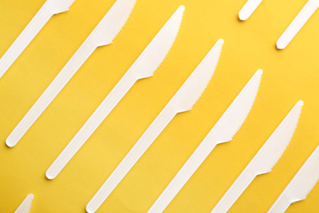 Plastic knives on color background, top view. Picnic table settingの写真素材