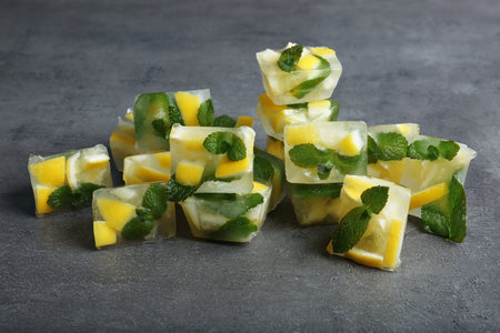 Ice cubes with mint and lemon on gray background