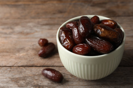 Bowl with sweet dates on table, space for text. Dried fruit as a healthy snack