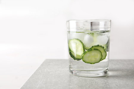 Glass of fresh cucumber water on table. Space for textの写真素材