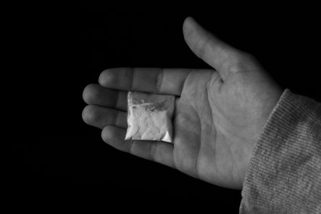 Drug dealer holding bag with cocaine on black background, closeupの写真素材