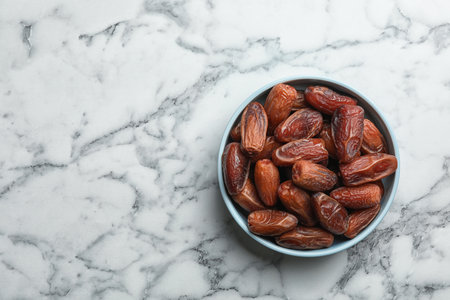 Bowl with sweet dried date fruits on marble background, top view. Space for textの写真素材