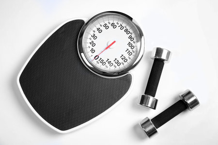 Modern scales and dumbbells on white background, top viewの写真素材