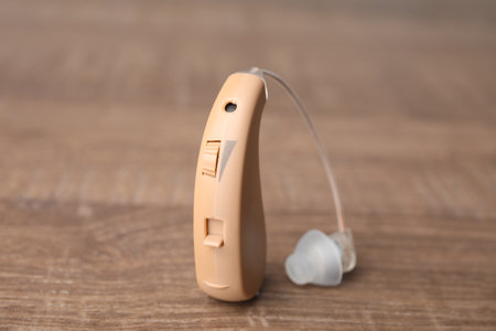 Hearing aid on wooden table, closeup. medical device