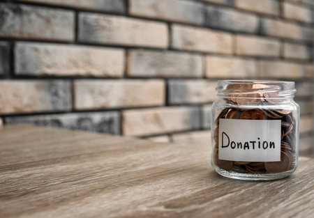 Donation jar with coins on table. Space for textの写真素材