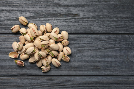 Heap of organic pistachio nuts on wooden table, top view. Space for textの写真素材