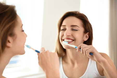 Young beautiful woman with toothbrush near mirror in bathroom. personal hygieneの写真素材
