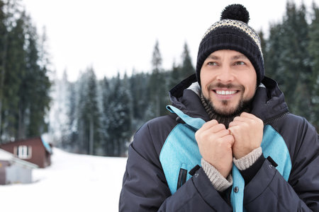 Happy man in warm clothes outdoors, space for text. winter holidays
