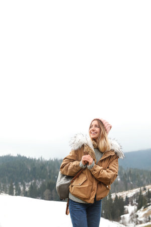 Young woman in warm clothes near snowy hill. winter holidaysの写真素材