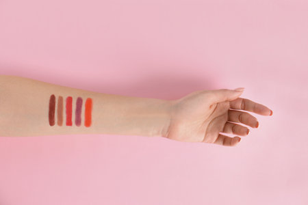 Woman with lipstick swatches on color background, closeup of handの写真素材