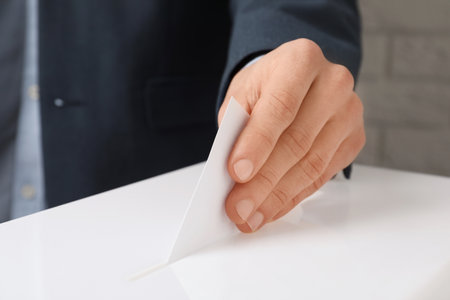 Man putting his vote into ballot box against brick wall, closeupの写真素材
