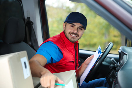 Young courier checking amount of parcels in delivery van