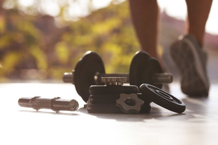 Adjustable dumbbells and male athlete on background. Space for textの写真素材
