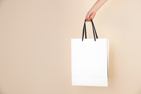 Woman holding paper shopping bag on color background. Mock up designの写真素材