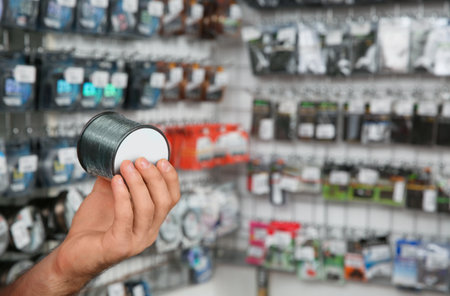 Salesman showing fishing equipment in sports shop, closeup. Space for textの写真素材