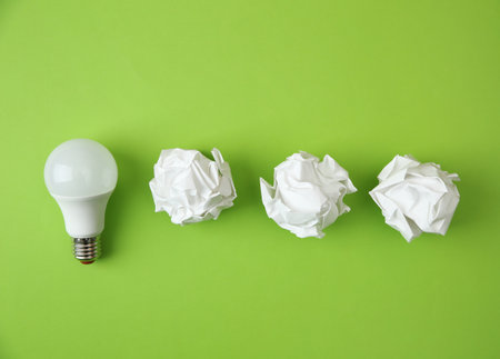 Flat lay composition with lamp bulb and crumpled paper on color backgroundの写真素材