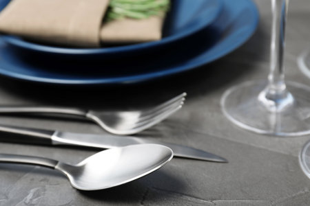 Cutlery and blurred plates with napkin on tableの写真素材
