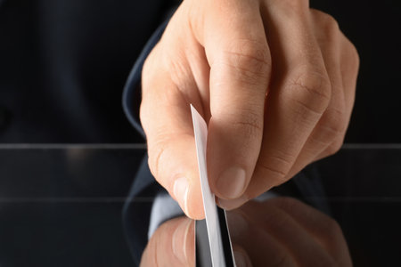 Man putting his vote into ballot box on black background, closeupの写真素材