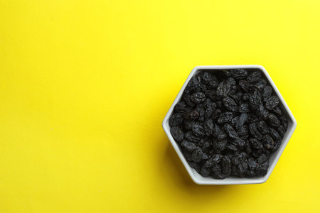 Bowl with raisins and space for text on color background, top view. Dried fruit as a healthy snackの写真素材