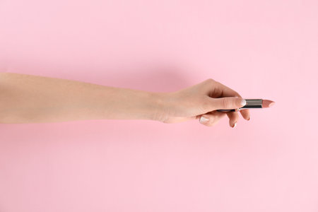 Woman holding lipstick on color background, closeupの写真素材
