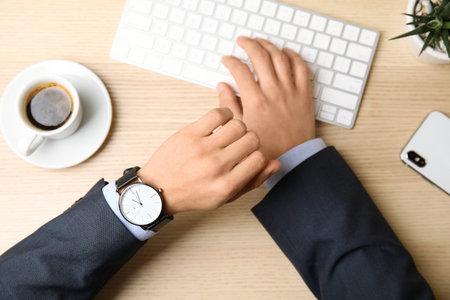 Businessman with wrist watch working at office table, closeup. time managementの写真素材