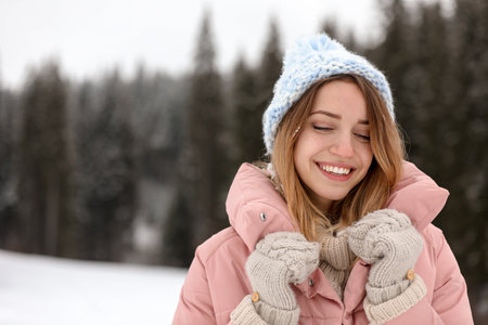 Young woman in warm clothes outdoors, space for text. winter holidays