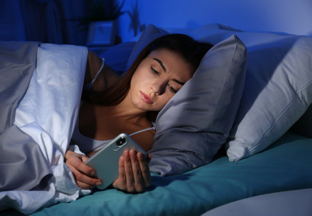 Young woman with mobile phone at night. Bedtimeの写真素材
