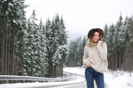 Young woman near snowy forest, space for text. winter holidays