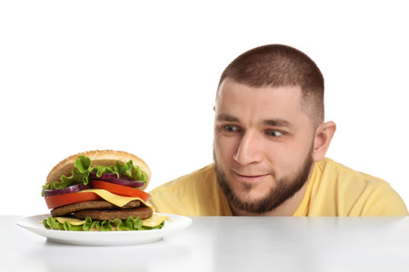 Young man and tasty burger on white backgroundの写真素材