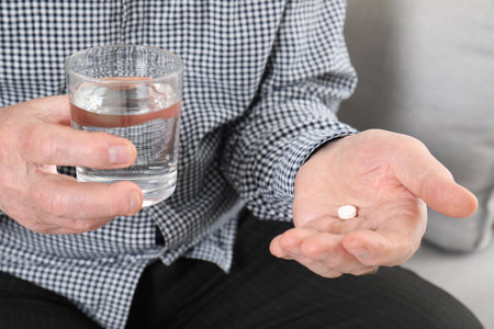 Senior man holding pill and glass of water, closeupの写真素材