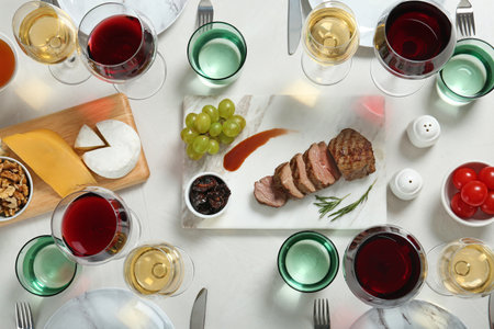 Wine and snacks served for dinner on light table, flat lay