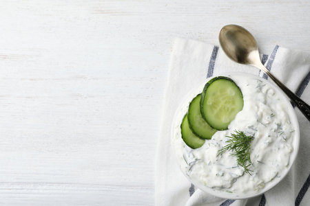 Cucumber sauce, spoon and space for text on wooden background, flat lay. Traditional Tzatzikiの写真素材