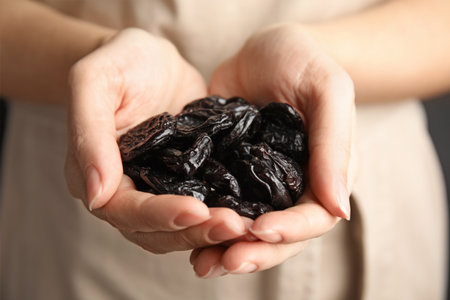 Woman holding handful of dried plums, closeup. Healthy fruitsの写真素材
