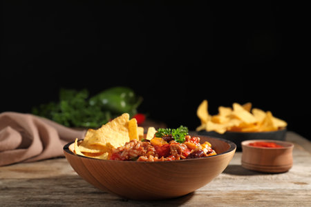 Tasty chili con carne served with tortilla chips in bowl on tableの写真素材