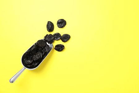 Scoop of dried plums on color background, top view with space for text. Healthy fruitsの写真素材