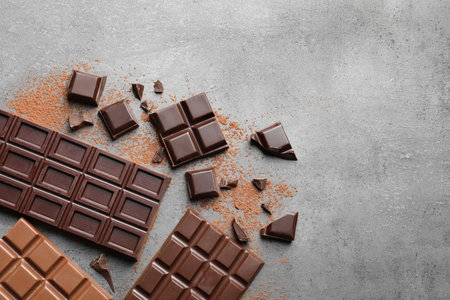 Different kinds of chocolate on gray background, flat lay. Space for text